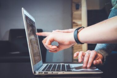 Teammates collaborating on a computer while exploring intelligent search and its impact on modern business operations